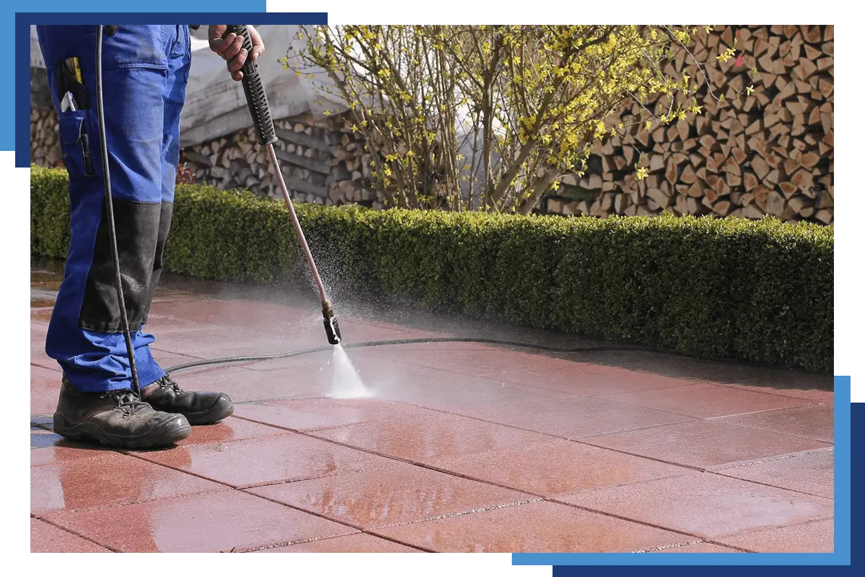 A person using a power washer on the patio